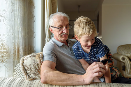 Grandfather with grandson using mobile phone. Looking video, making call
