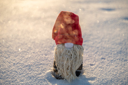 Handmade Christmas gnome on snow. Upcycle, made from old socks. Center composition, backlit sun,...
