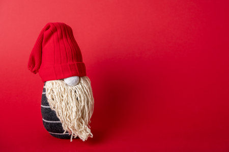 Handmade Christmas gnome on red background. Upcycle, made from old socks. Copy space on rightの写真素材