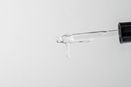 Pipette with liquid transparent gel, serum or essential oil on light grey backgroundの写真素材