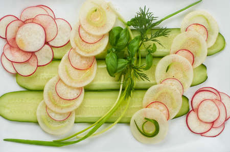 Cucumber, radish, daikon and greens salad on a white plate. Top view. Close-up.の写真素材