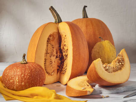 Orange pumpkins of various sizes on a light table, several slices have been cut off from one of the pumpkins.の写真素材
