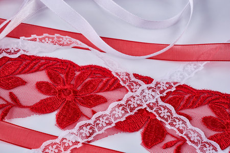 Various red and white lace and satin ribbons lie on a white table, close-up. background.の写真素材