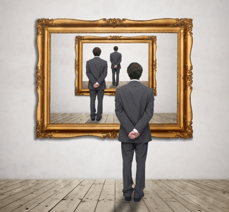 Image of businessman standing in front of a gold frame with his figureの写真素材