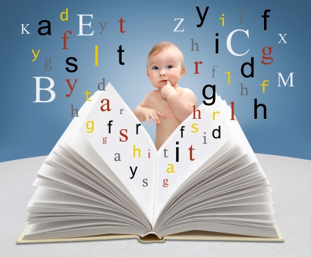 Little boy sitting with a book with flying lettersの写真素材