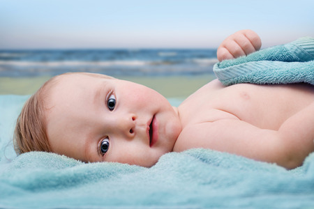 baby in a towel at the beachの写真素材
