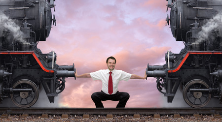 Young businessman pushes apart two steam locomotivesの写真素材