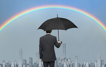 Man with black umbrella watching the rainbowの写真素材