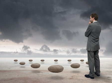 young businessman looking at flying stonesの写真素材