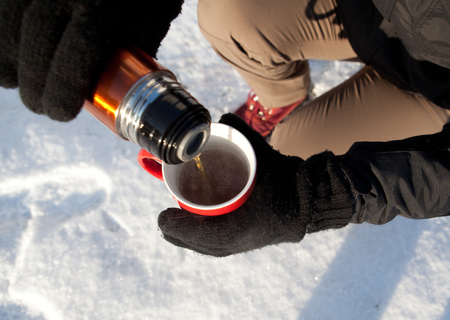 tourist pours coffee from a thermos on frostの写真素材