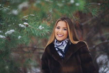 Happy, young europian model with beautiful smile walk in the winter snowy forestの写真素材
