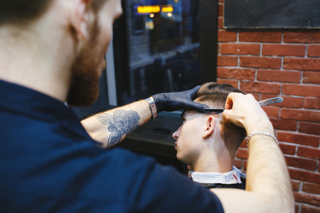 Hairdresser shaving young man with a straight razorの写真素材