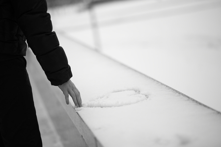 Man draw heart on snow background. With space for text. Black-and-white.の写真素材