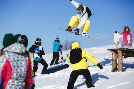 Snowboarder jump from wooden springboard in the mountainsの写真素材