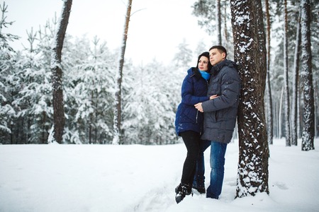 happy loving couple walking in snowy winter forest, spending christmas vacation together. Outdoor seasonal activities. Lifestyle capture.の写真素材