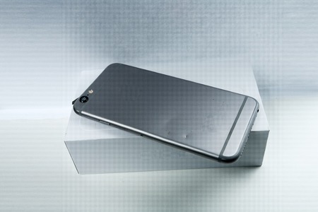 Modern mobile phone with broken back panel side on white background.
