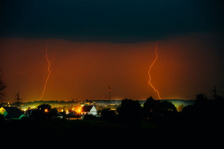 Cloud to Ground Electric Lightning behind house roof tops.