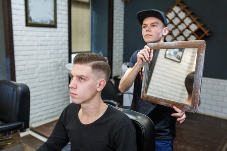 Master cuts hair of men in the barbershop, hairdresser makes hairstyle for a young man.の写真素材
