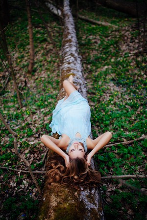outdoor portrait of a beautiful brunette model in blue dress in the spring forest.の写真素材