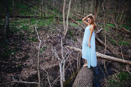 outdoor portrait of a beautiful brunette model in blue dress in the spring forest.の写真素材
