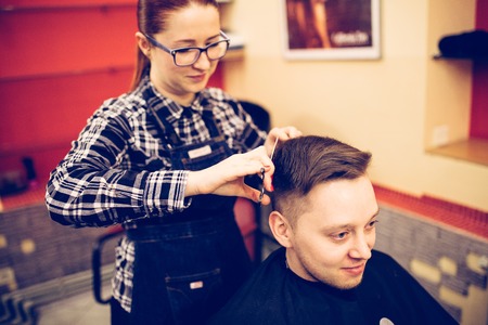 young attractive woman hairdresser make hairstyle for man.