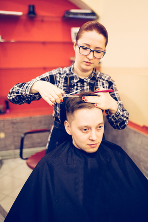 young attractive woman hairdresser make hairstyle for man.の写真素材
