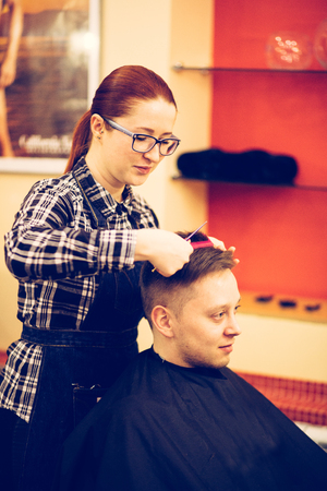 young attractive woman hairdresser make hairstyle for man.の写真素材