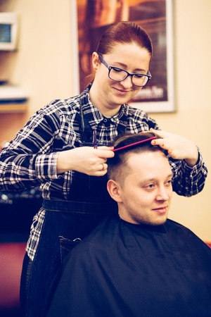 young attractive woman hairdresser make hairstyle for man.の写真素材