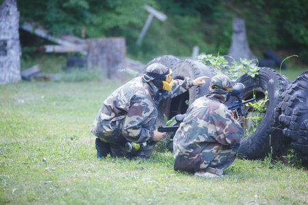 Paintball sport player in uniform and mask with gun outdoors.の写真素材