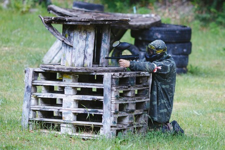 Paintball sport player in uniform and mask with gun outdoors.の写真素材