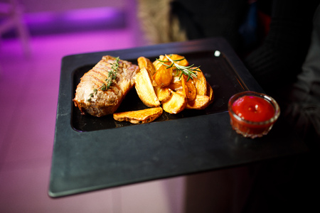 Big black plate with fried potatoes, meat and tomato sauceの写真素材