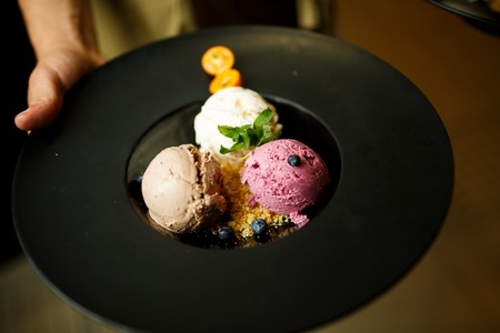 Balls of ice cream with berries in the black plate.の写真素材