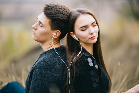 Loving couple listens music together outdoor in autumn.の写真素材