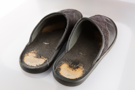 Old black slippers isolated on white background.
