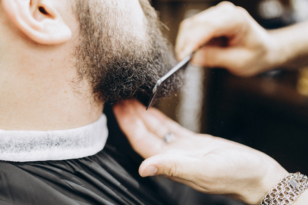 Man hairdresser comb a beard in barbershop.の写真素材