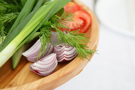 Organic farm. Fresh vegetables in wooden plate: yellow and red bell pepper, onion, tomato and cucumbersの写真素材