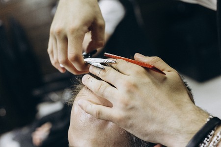 Hairdresser doing hair in the barber shop with scissors
