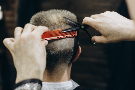 Hairdresser doing hair in the barber shop with scissorsの写真素材