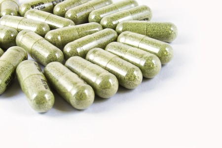 green herbal medicine capsule isolated on white backgroundの写真素材