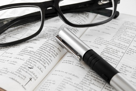 closeup of old dictionary and black glasses with penの写真素材
