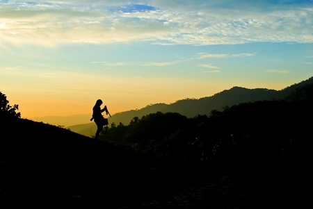 Silhouette of photographer on the mountain over the twilight skyの写真素材