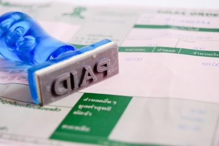 paid letter on rubber stamp with business cash receipt paper backgroundの写真素材