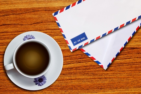 air mail envelope and coffee cup on wood table background