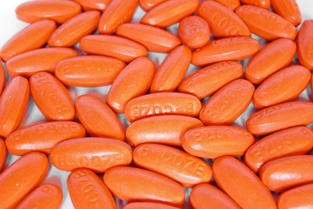 orange vitamin medicine pills closeup on white background