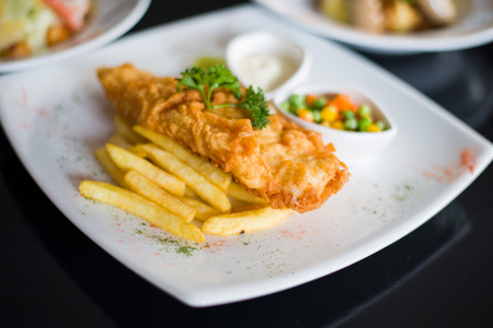 fish and chips served with tartar sauce and vegetables