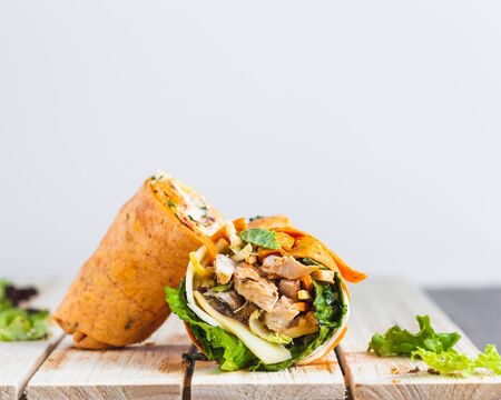 Chicken cheese and lettuce wrap on light grey background light wood surface nicely composedの写真素材