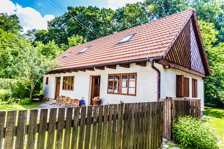View of traditional village house with blue sky, fence and trees-Czech republicのeditorial素材