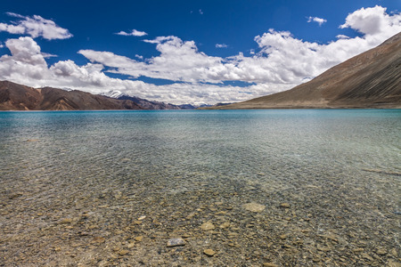 Beautiful blue and turquoise Pangong Tso lake with deep blue sky and white clouds and stones in the lake - Ladakh, Indiaの写真素材