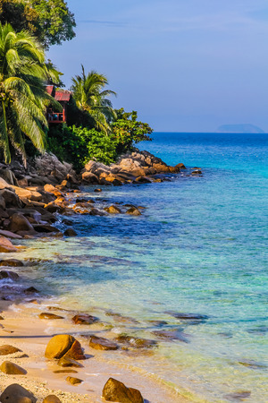 Turquoise Sea and Tranquil Empty Beach with Stones, Deep Blue Sky and Palm Trees - Perhentian Islands, Malaysiaの写真素材