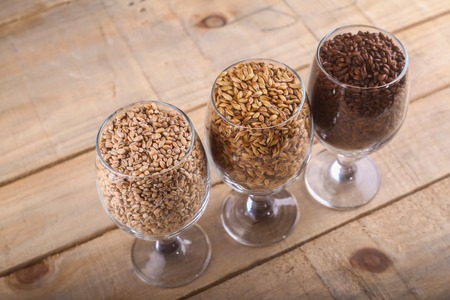 Glasses filled with different types of malt over a wooden backgroundの写真素材